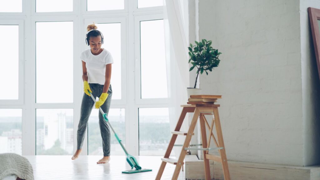 A person mopping the floor in a bright, tidy room