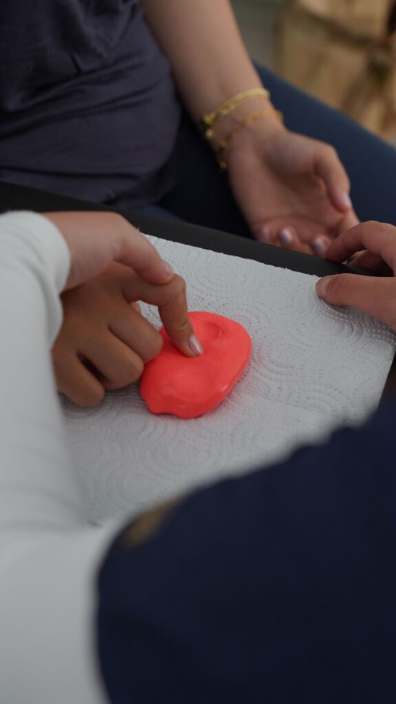 A young child’s hands exploring colourful clay during sensory play